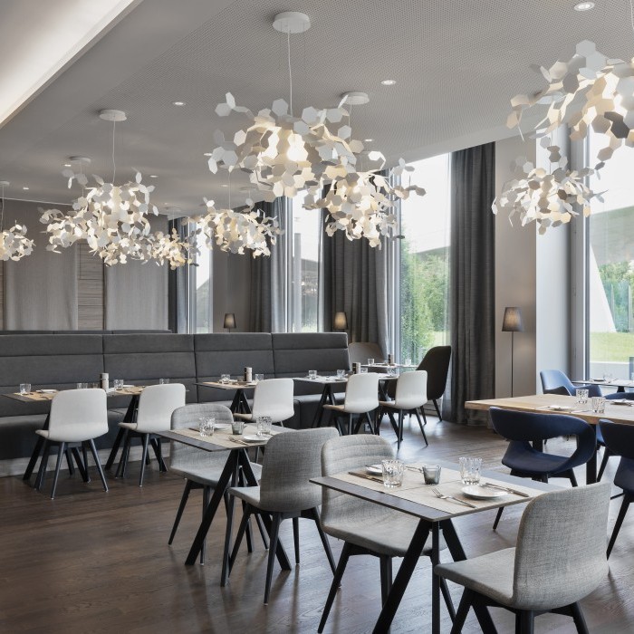 Elegantes Restaurant mit modernem Mobiliar, hölzernem Boden und organisch geformten Leuchten in einem Hotel nahe dem Flughafen München.