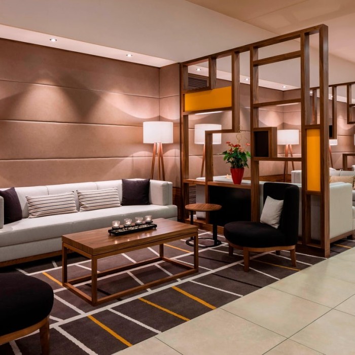 Elegante Hotel-Lounge mit bequemen Sofas, warmem Holzdekor, moderner Beleuchtung und einem stilvollen Teppichdesign im Flughafenhotel München (Freising).
