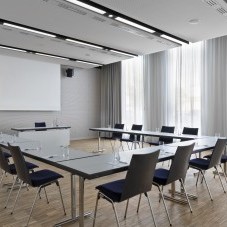 Heller und moderner Meetingraum im Science Congress Center Munich mit U-förmiger Tischanordnung und großer Leinwand.