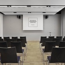 Heller Konferenzraum im Science Congress Center Munich mit Bestuhlung in Reihen und einer Präsentationsleinwand.