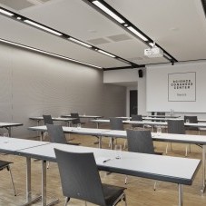 Moderner Tagungsraum im Science Congress Center Munich mit Tischen, Stühlen und einer großen Leinwand.