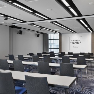 Moderner Konferenzraum im Science Congress Center Munich mit Reihenbestuhlung, Tischen und Leinwand für Präsentationen.