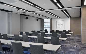 Moderner Konferenzraum im Science Congress Center Munich mit Reihenbestuhlung, Tischen und Leinwand für Präsentationen.
